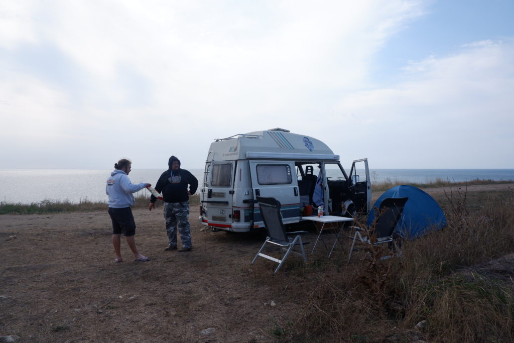 Caravan parked on a cliffy shore.